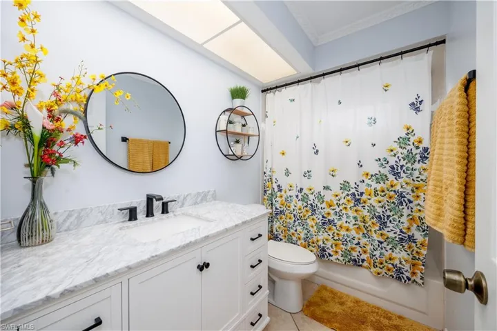 Full bath featuring crown molding, toilet, shower / bath combination with curtain, tile patterned floors, and vanity