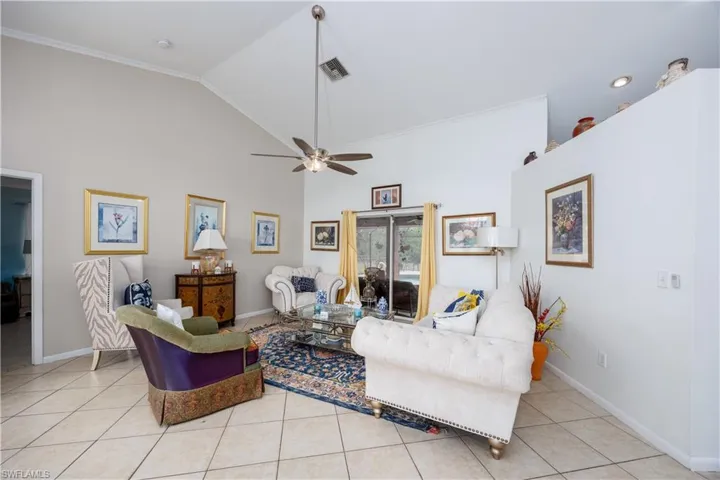 Living area featuring light tile patterned floors, crown molding, a ceiling fan, visible vents, and baseboards