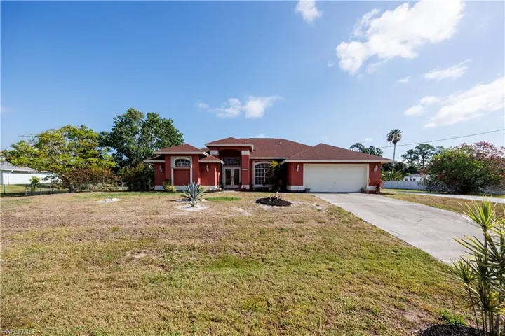 View of front facade featuring a front lawn, driveway, an attached garage, and stucco siding