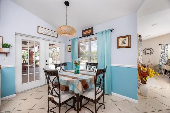 Dining space with light tile patterned floors, french doors, vaulted ceiling, and baseboards
