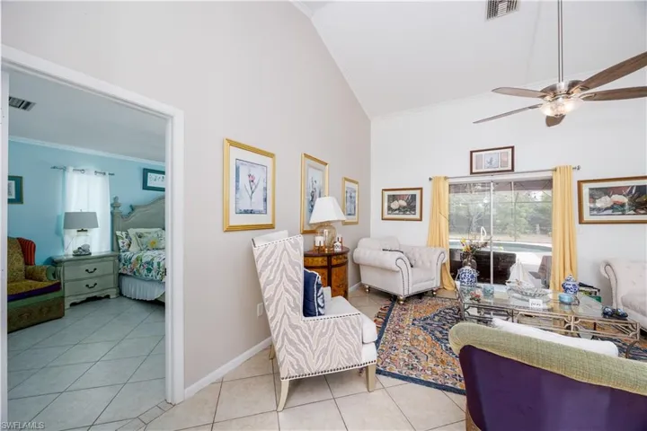 Living area with ornamental molding, tile patterned flooring, visible vents, and high vaulted ceiling