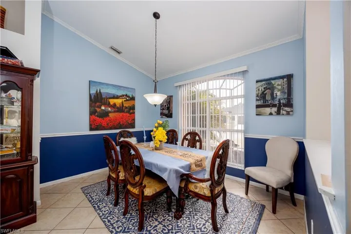 Dining room with light tile patterned floors, crown molding, visible vents, and vaulted ceiling