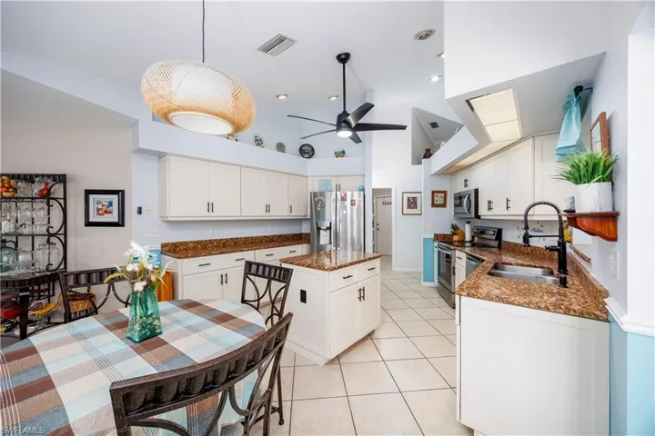 Kitchen featuring white cabinetry, a sink, stainless steel appliances, a center island, and a ceiling fan