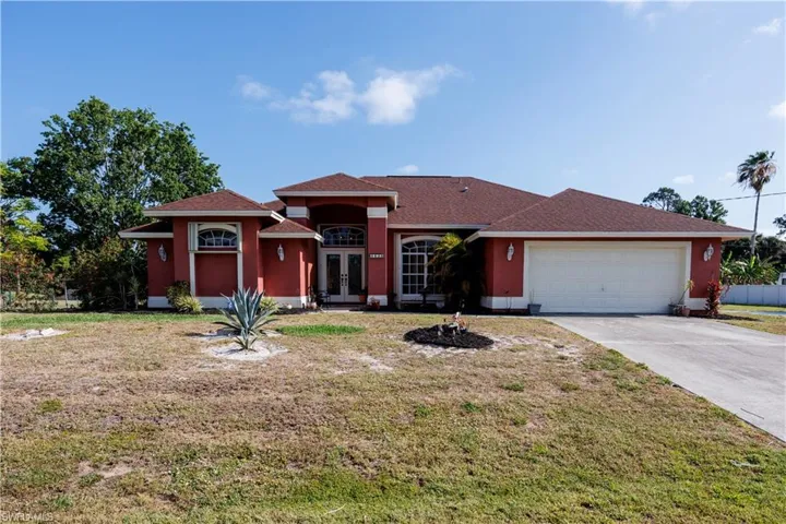 View of front of home featuring concrete driveway, a front yard, french doors, and an attached garage