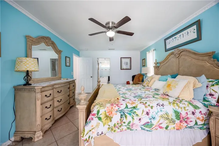 Bedroom featuring ornamental molding, light tile patterned flooring, and a ceiling fan