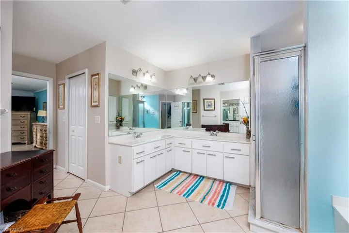 Bathroom with a shower with shower door, vanity, and tile patterned flooring