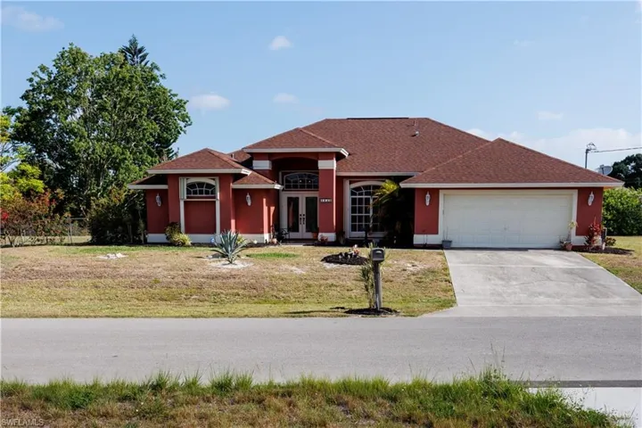 View of front of house with concrete driveway, a front yard, a garage, and french doors