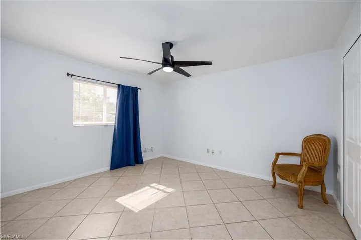 Spare room with light tile patterned flooring, a ceiling fan, and baseboards