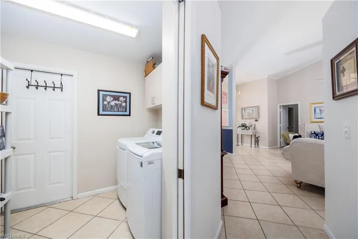 Laundry area with baseboards, cabinet space, light tile patterned flooring, and independent washer and dryer