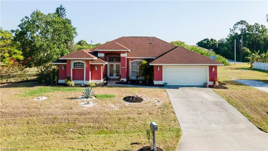 View of front of property with french doors, a front lawn, driveway, and an attached garage