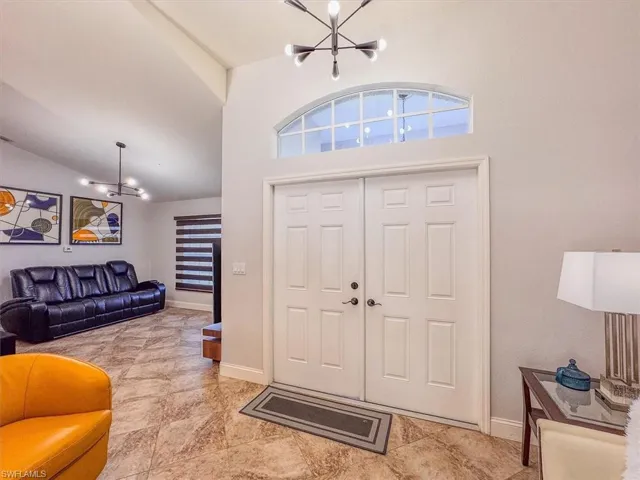 Foyer entrance with baseboards, lofted ceiling, and a chandelier