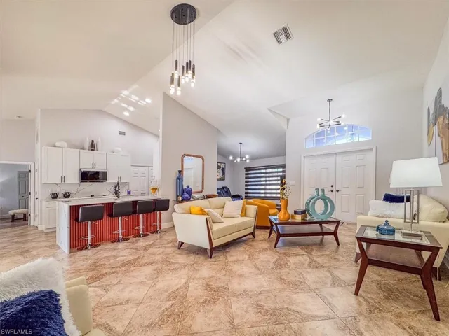 Living area featuring visible vents, high vaulted ceiling, and an inviting chandelier