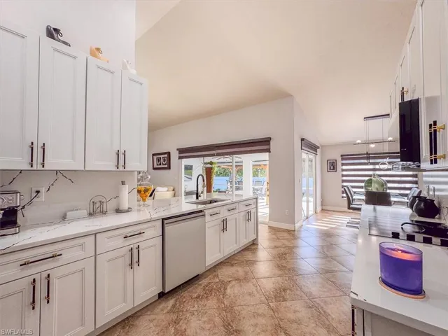 Kitchen with dishwasher, a sink, white cabinetry, and backsplash