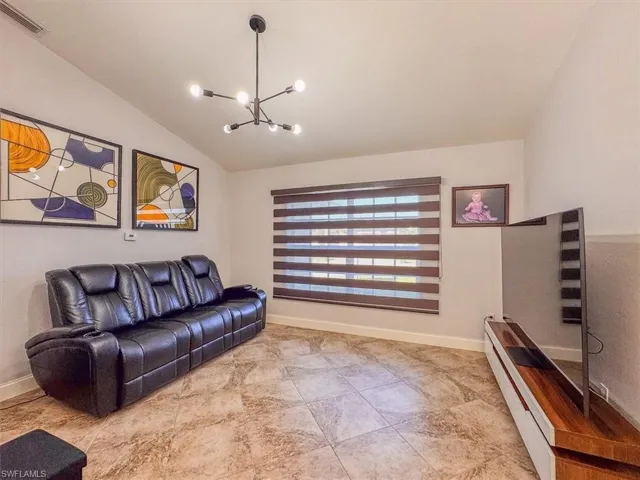 Living room with an inviting chandelier, baseboards, vaulted ceiling, and visible vents