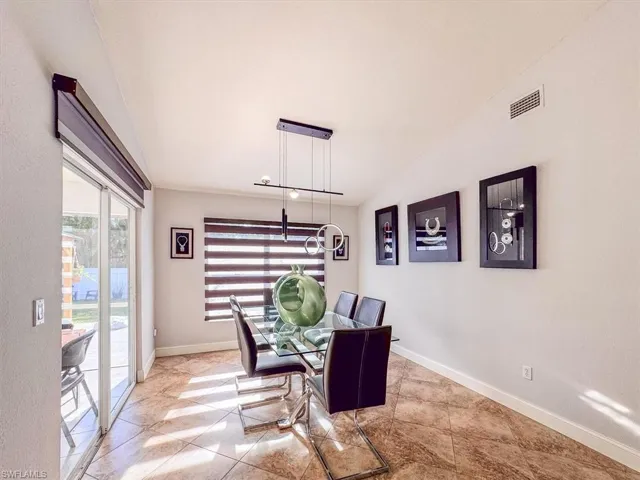 Dining room featuring baseboards, visible vents, vaulted ceiling, and a notable chandelier