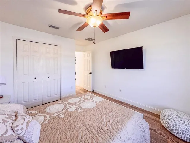 Bedroom featuring light wood finished floors, baseboards, visible vents, and a closet