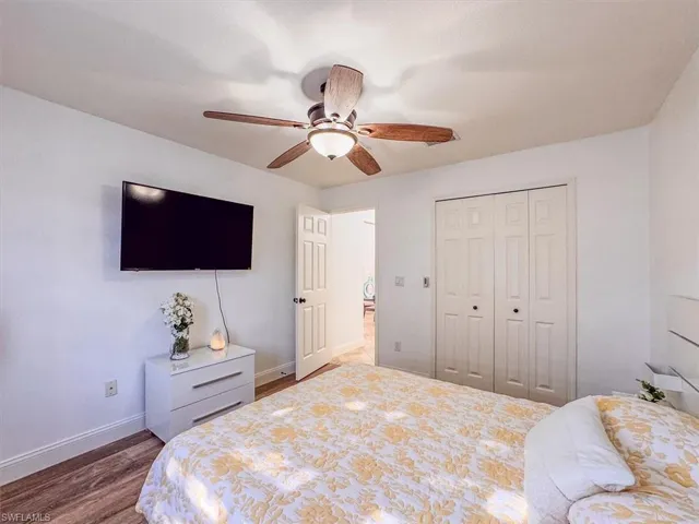 Bedroom with a closet, baseboards, wood finished floors, and a ceiling fan
