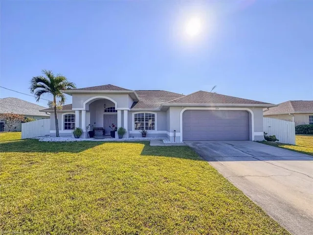 View of front facade featuring driveway, stucco siding, and fence