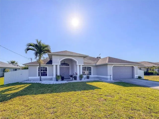 View of front of home featuring driveway, fence, a garage, a front yard, and stucco siding