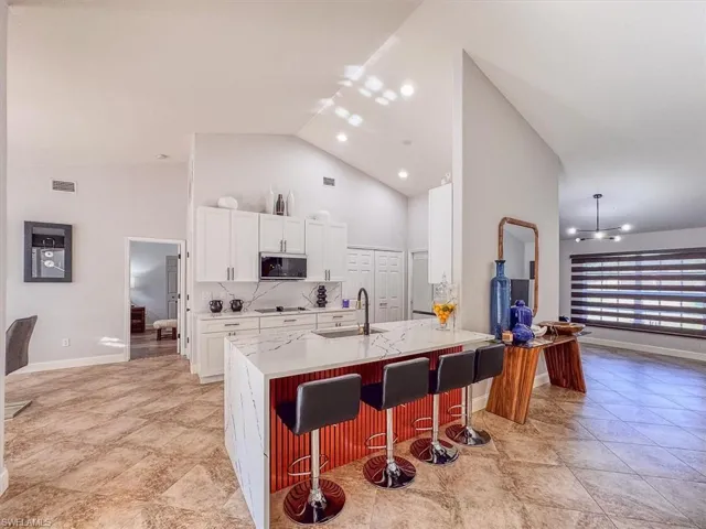 Kitchen featuring a sink, white cabinetry, a kitchen breakfast bar, stainless steel microwave, and visible vents