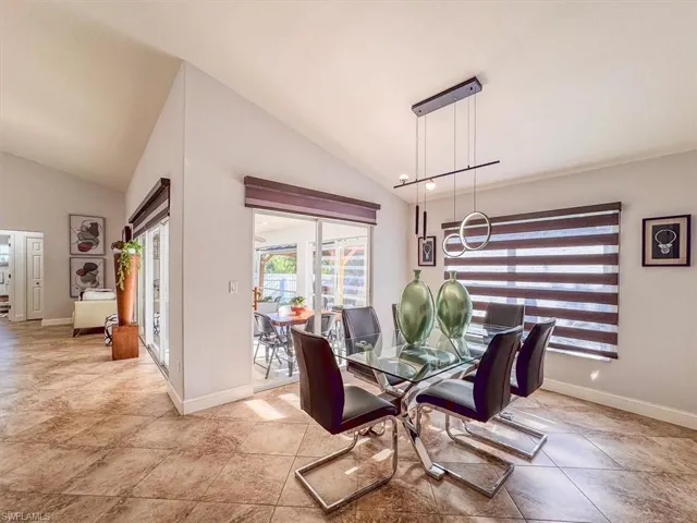 Dining space with baseboards, high vaulted ceiling, and an inviting chandelier
