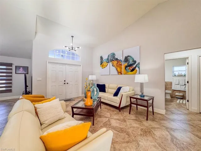 Living room featuring baseboards, high vaulted ceiling, and a chandelier