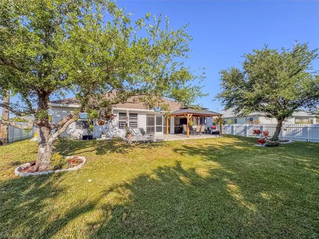 Rear view of property featuring a sunroom, a patio, a fenced backyard, a gazebo, and a lawn