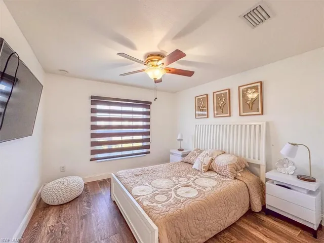 Bedroom with baseboards, ceiling fan, visible vents, and wood finished floors