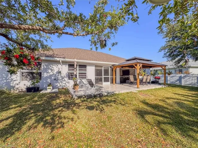 Rear view of property with fence, a patio, a gazebo, stucco siding, and a lawn