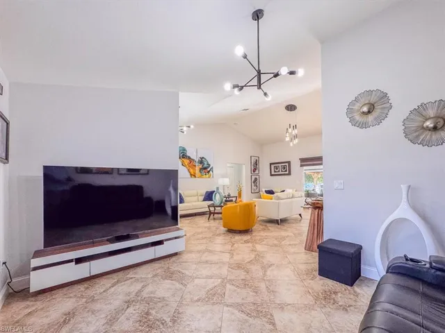 Living area featuring baseboards, lofted ceiling, and a chandelier