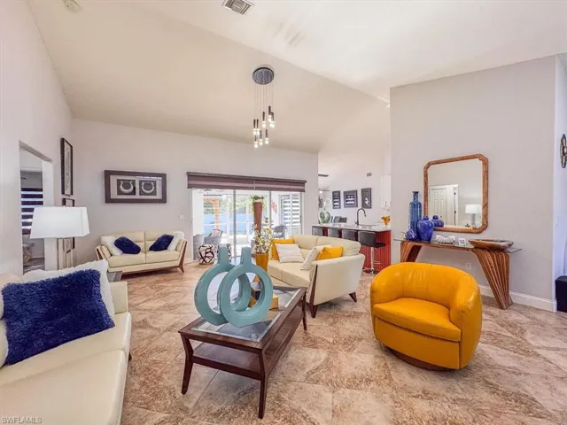 Living room featuring baseboards, vaulted ceiling, and visible vents