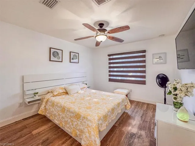 Bedroom with baseboards, visible vents, and wood finished floors