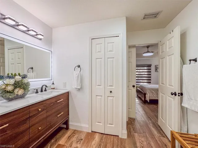 Full bathroom featuring vanity, a closet, visible vents, ensuite bathroom, and wood finished floors