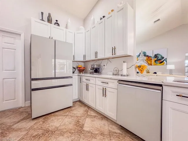 Kitchen featuring white appliances, visible vents, light countertops, and white cabinetry