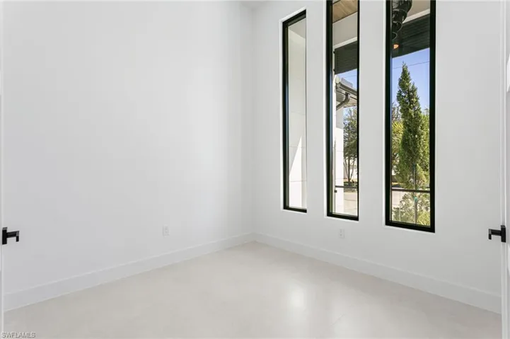 This stunning oasis luxury home features an elegant den, perfect for a private office or cozy retreat, with expansive windows offering breathtaking views of the lush surroundings.