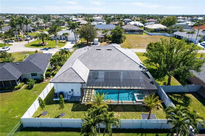 OVERSIZED HEATED SALTWATER POOL & INTEGRATED JACUZZI SPA, surrounded by ARTIFICIAL GRASS, MARBLE, LUSH LANDSCAPING & FENCED YARD.