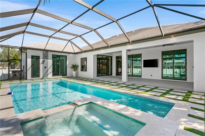 STEP OUTSIDE to YOUR OASIS, featuring OVERSIZED HEATED SALTWATER POOL & INTEGRATED JACUZZI SPA, surrounded by ARTIFICIAL GRASS, MARBLE, LUSH LANDSCAPING & FENCED YARD.