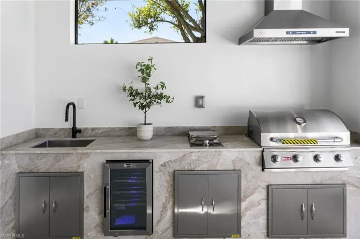OUTDOOR KITCHEN w/ TAJ MAHAL MARBLE, SS BULL 4-BURNER propane grill, SIDE BURNER, mini-refrigerator & commercial sink.