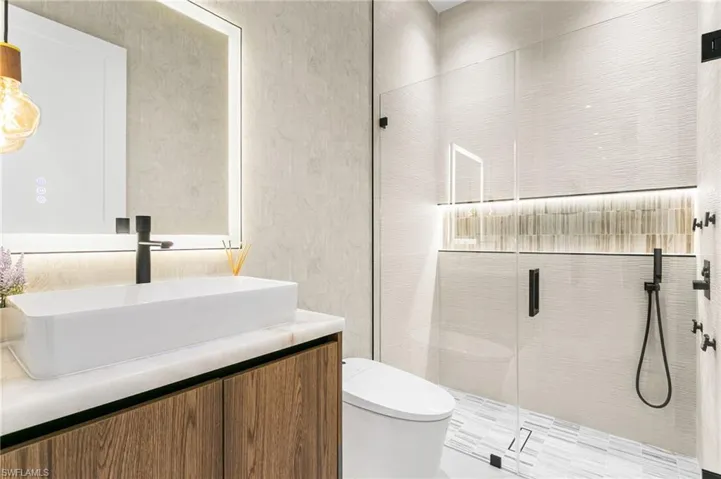 Hallway bathroom with Italian wallpaper, electric toilet, LED lights, lighted mirrors, vessel sink and designer's light! Rainfall shower with 4-jets and handheld shower heads.