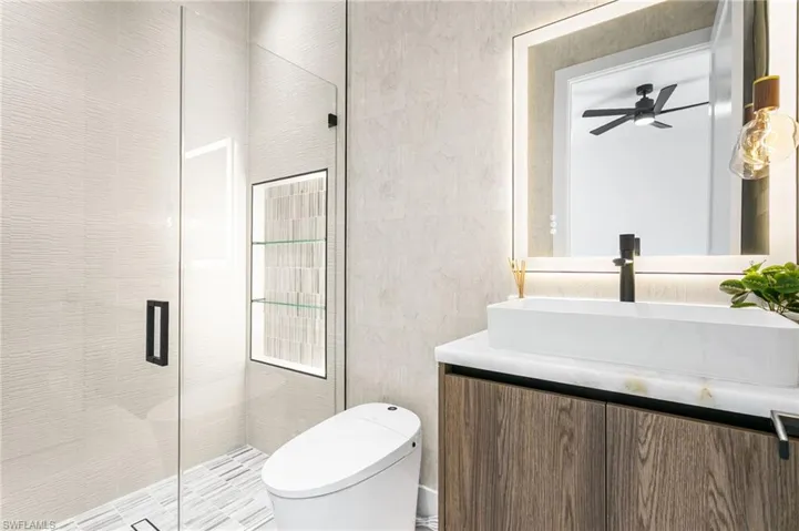 Secondary master bathroom with Italian wallpaper, electric toilet, LED lights, lighted mirrors, vessel sink and designer's light! Rainfall shower with 4-jets and handheld shower heads.