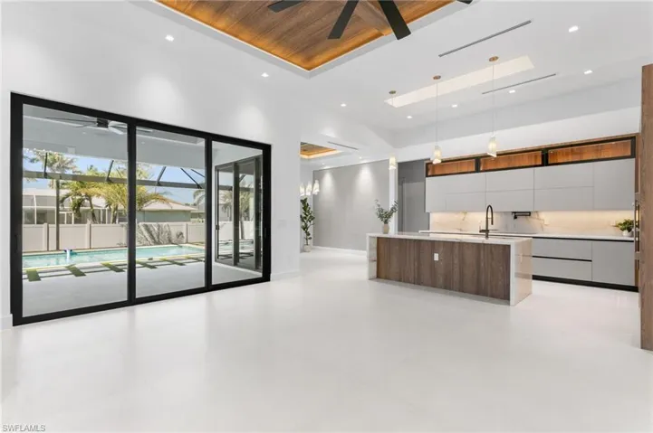 AWE-INSPIRING LIVING ROOM w/ 16-ft cove ceiling, FLAT WOODEN PANELS, ITALIAN WALLPAPERED FEATURE WALL w/ cabinets & LED-LIT SHELVING, 75" TV & integrated BOSE SURROUND SOUND SUSTEM creates AMBIANCE for RELAXATION or MOVIE NIGHTS.
