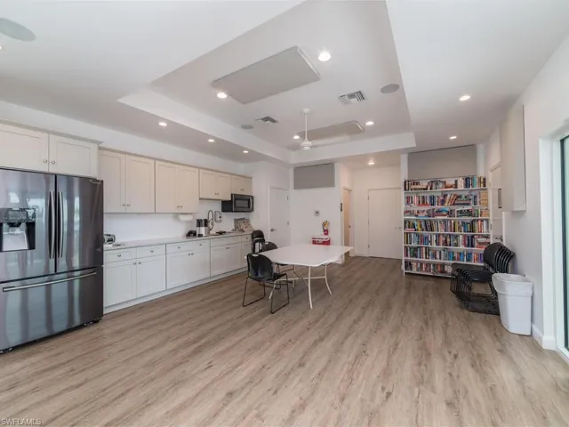 Kitchen with white cabinets, appliances with stainless steel finishes, a tray ceiling, and light hardwood / wood-style flooring