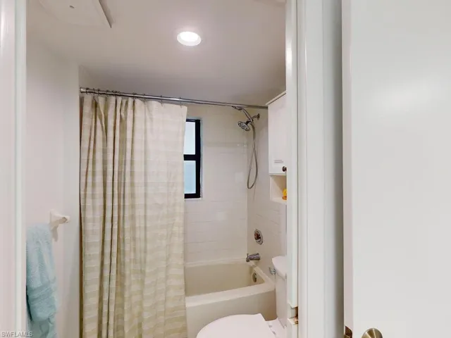 Bathroom with toilet and shower / tub combo with curtain