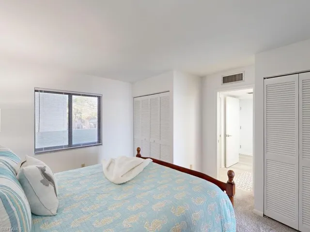 Bedroom featuring light carpet and two closets
