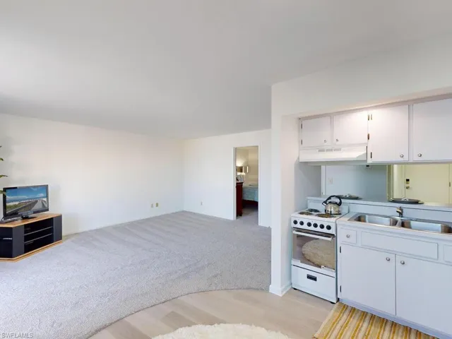 Kitchen with white cabinets, white range, sink, and light hardwood / wood-style flooring