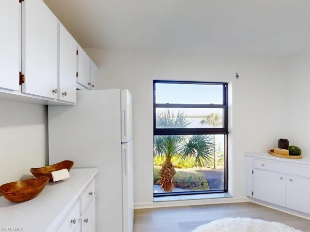 Kitchen with white fridge, plenty of natural light, white cabinets, and light hardwood / wood-style floors