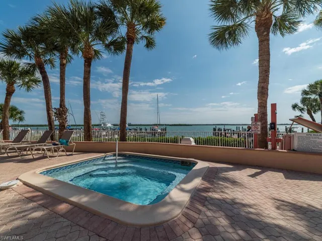 View of pool with a community hot tub, a water view, and a patio