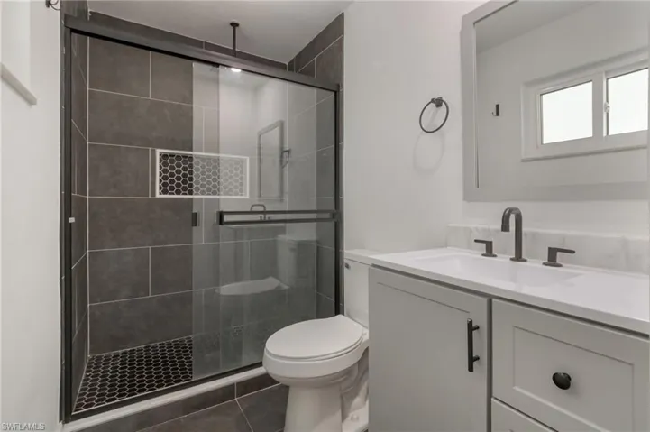 Modern bathroom featuring a glass-enclosed shower with dark tile walls and a hexagonal tile floor