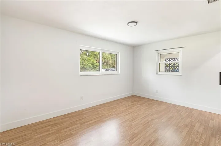 Neutral interior with wood-finish flooring, white walls, and bright white baseboards