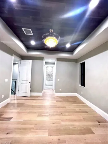 Spare room with a raised ceiling, light wood-style floors, and recessed lighting